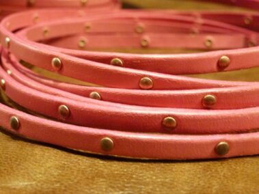 Pink leather strap with pink edges and copper colored rivets every 2.5 cm.