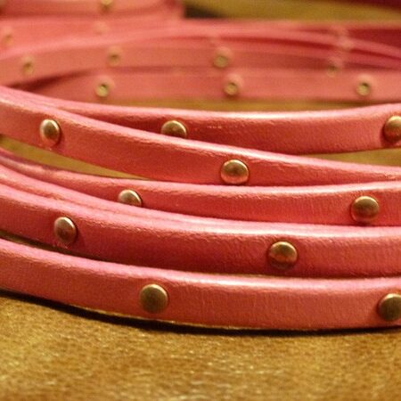 Pink leather strap with pink edges and copper colored rivets every 2.5 cm.